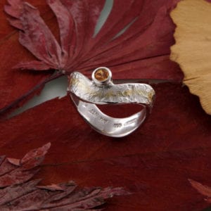 Geschwungener Eisschlagring mit Mandaringranat seitlich Gold und Silber